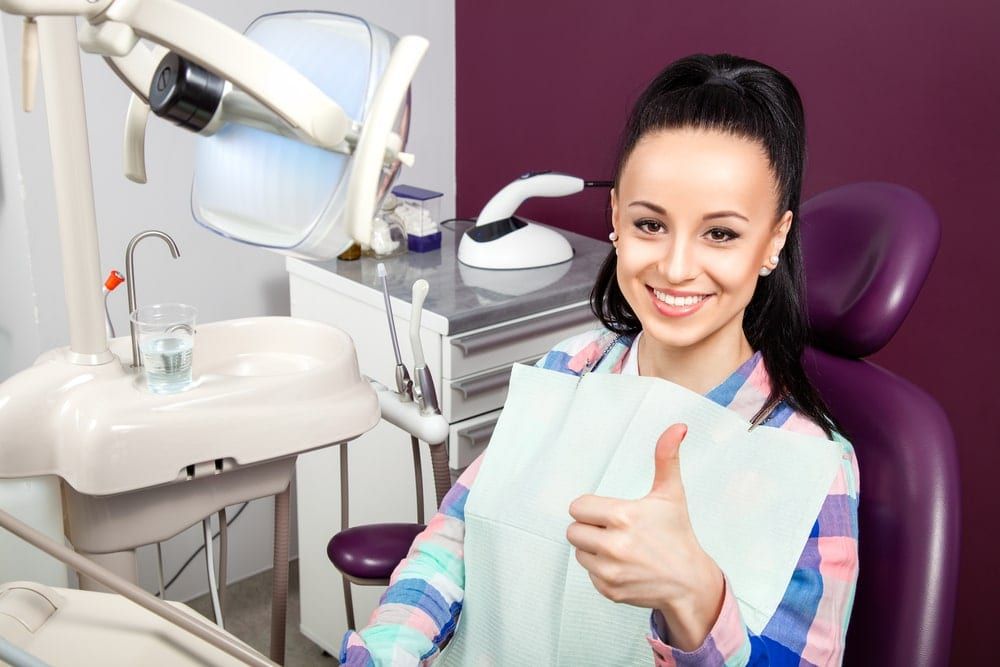 Woman in dental chair with a smile and thumbs up