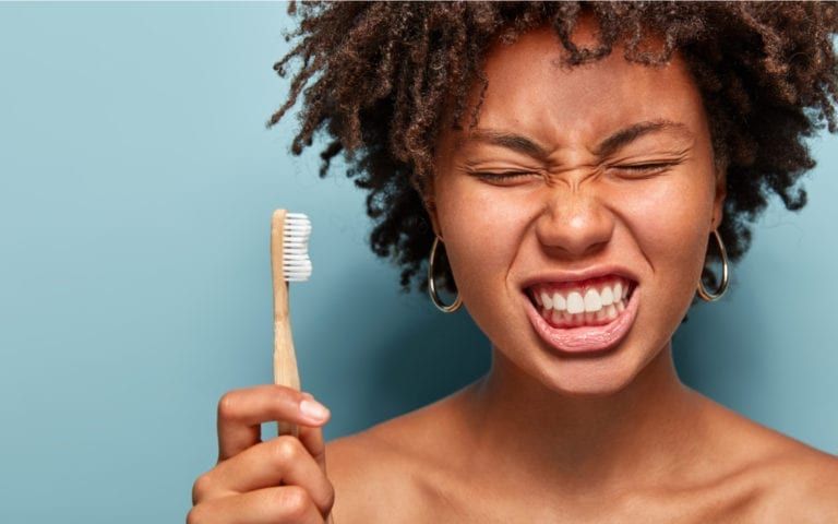Woman grimacing with toothbrush